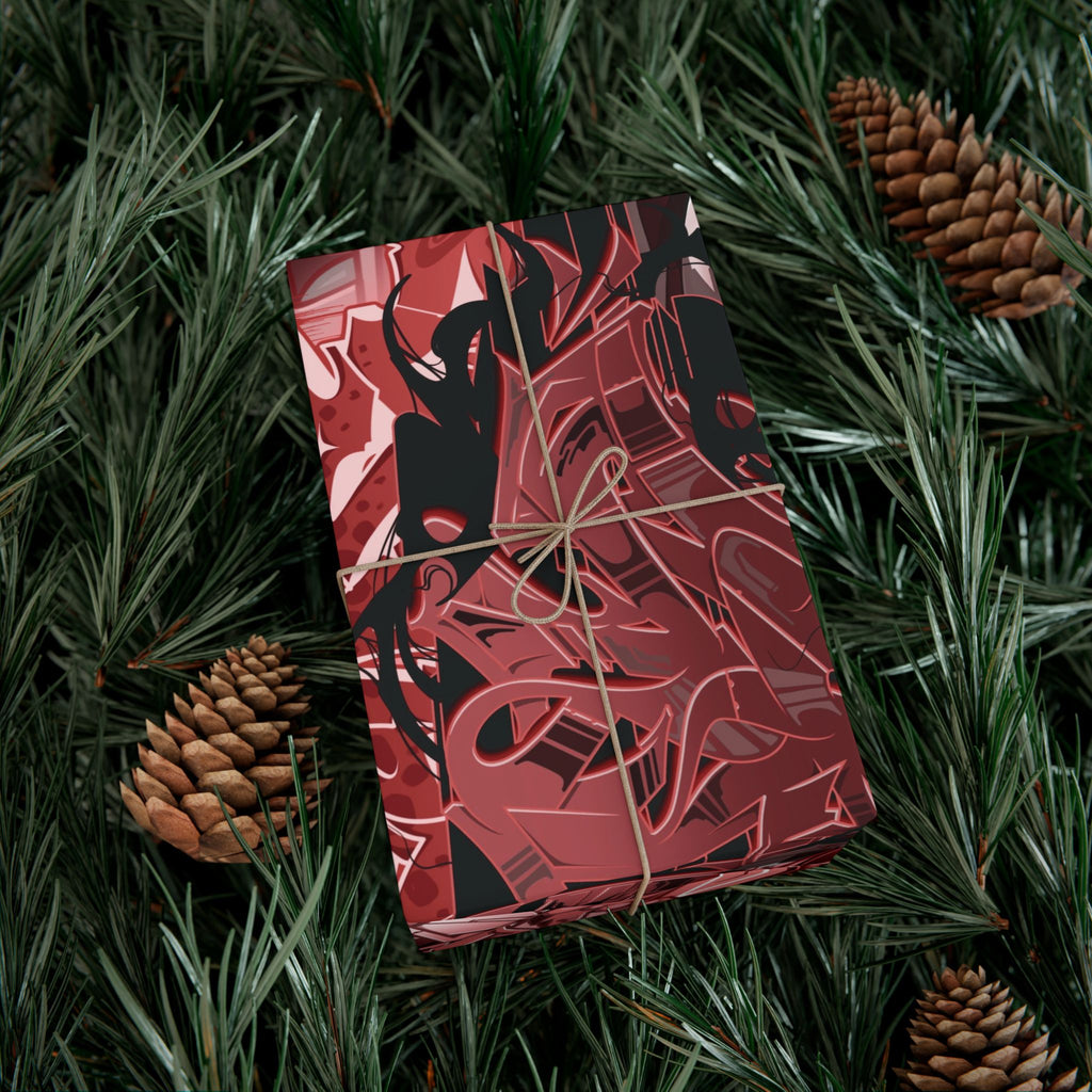 Red and black patterned gift box tied with string on a green leafy background with pine cones.