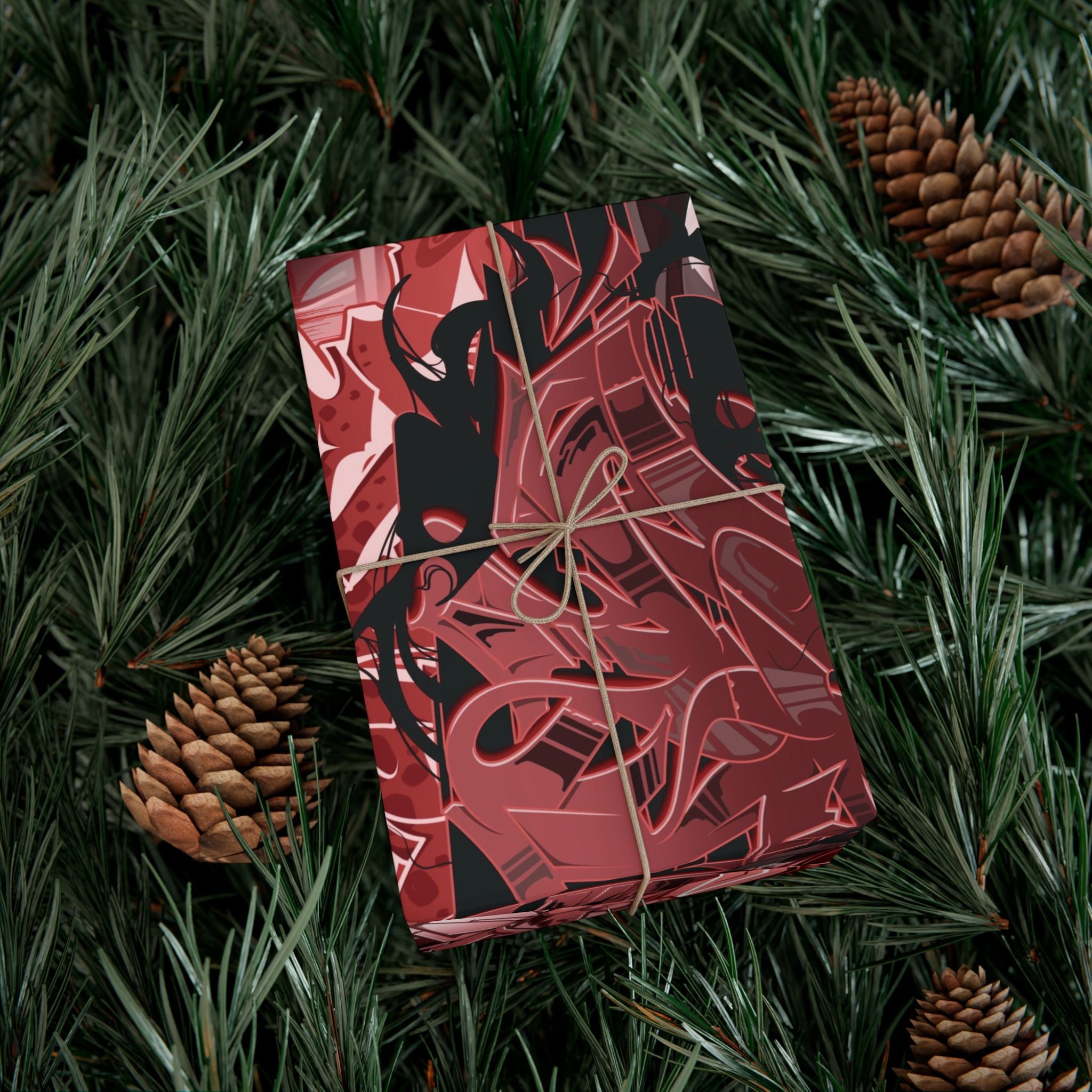 Red and black patterned gift box tied with string on a green leafy background with pine cones.