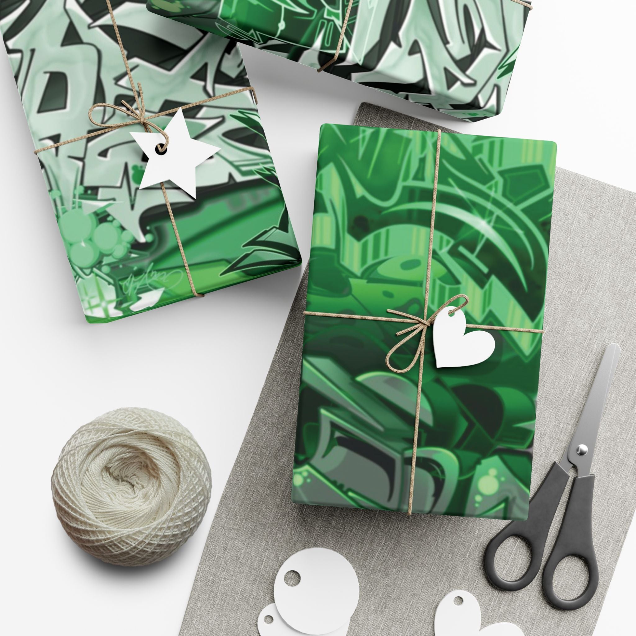 Green patterned gift boxes with decorative tags and scissors on a white surface