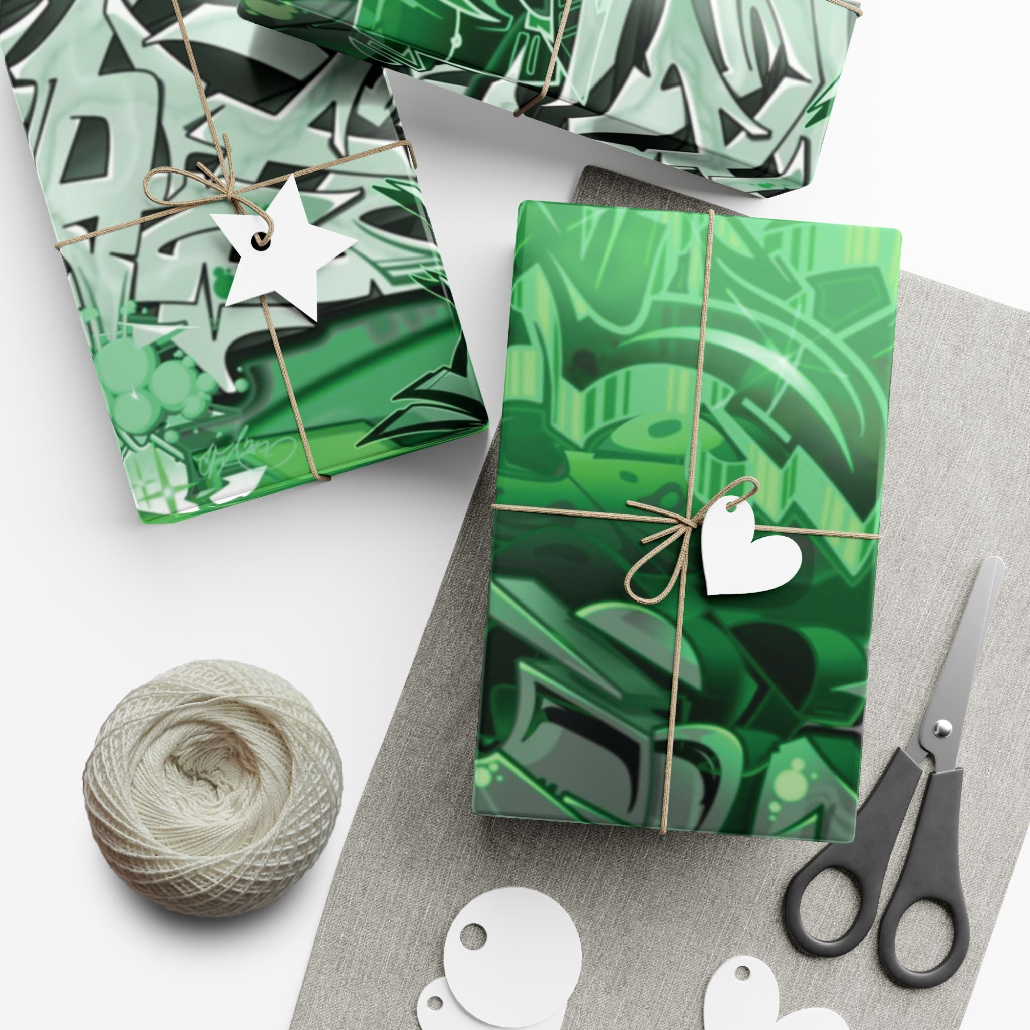 Green patterned gift box with decorative string, star and heart tags on a white surface.