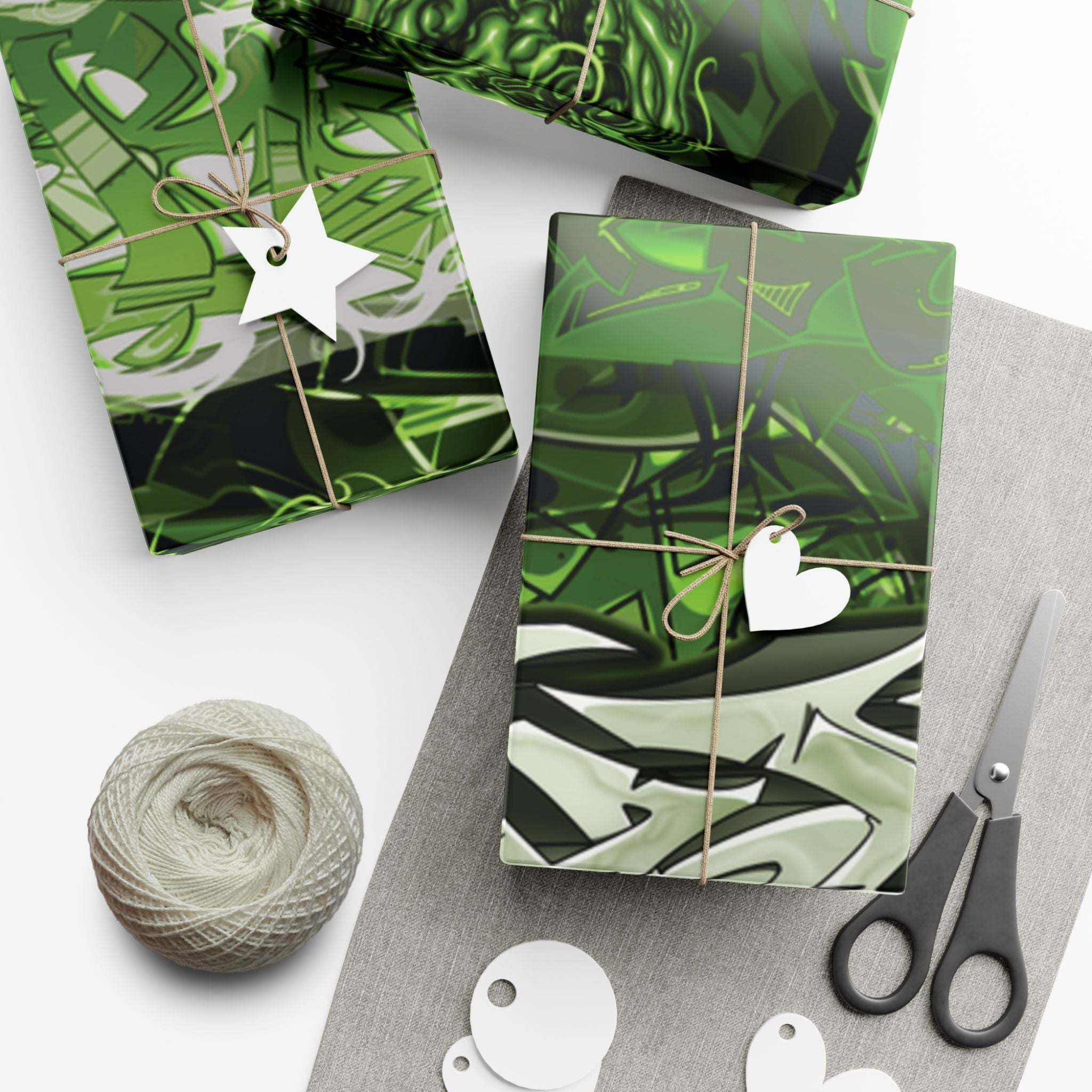 Green patterned gift boxes with decorative ribbons, tags, and scissors on a white surface.