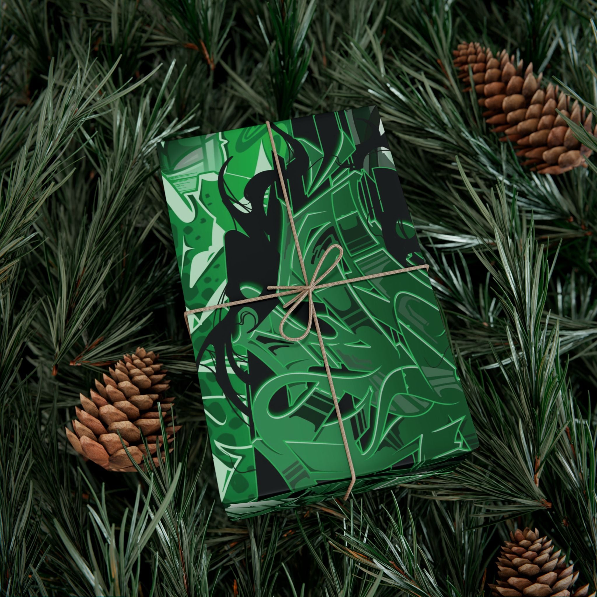 Green gift box with black patterns tied with brown string on a bed of pine needles and pine cones.