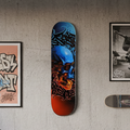 Skateboard deck with a colorful skull design on a textured wall with framed art.