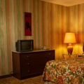 Vintage bedroom with striped wallpaper, television, and floral bedspread.